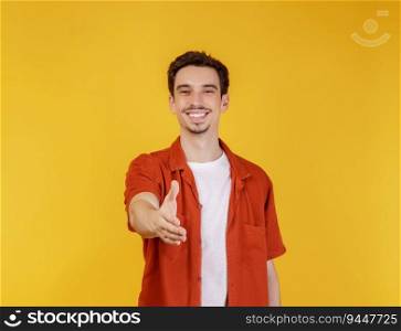 Portrait of smiling handsome man extend hand for handshake, look friendly, greet you, hi gesture, standing over yellow background