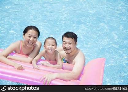 Portrait of smiling happy family floating in the pool on a inflatable raft