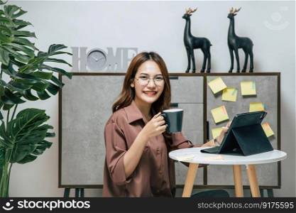 Portrait of smiling happy woman relaxing with coffee, using technology of digital pen on tablet to working from home during self-isolation and quarantine covid-19 coronavirus outbreak