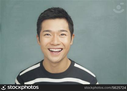 Portrait of smiling, happy young man in front of blackboard