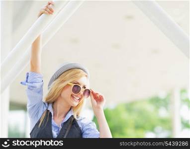 Portrait of smiling hipster girl in sunglasses in the city looking on copy space