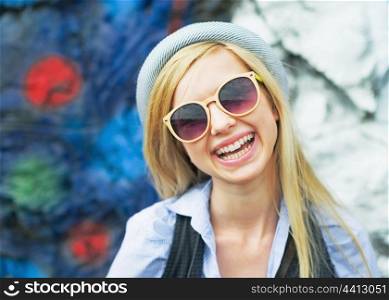 Portrait of smiling hipster girl wearing sunglasses outdoors