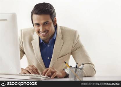 Portrait of smiling Indian businessman using computer at office desk