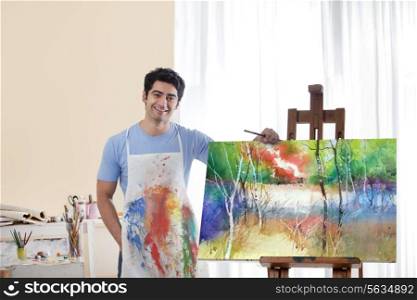Portrait of smiling male painter standing by his painting