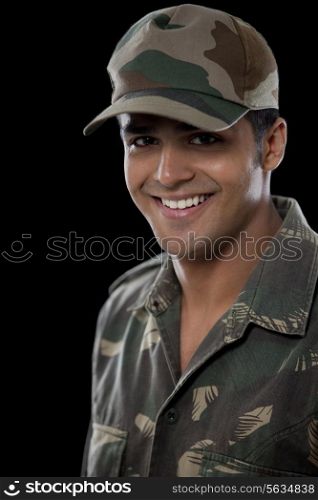 Portrait of smiling male soldier over black background