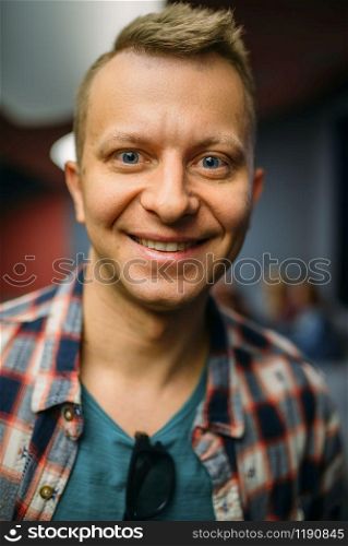 Portrait of smiling male spectator in cinema hall before the showtime. Man in movie theater, entertainment lifestyle