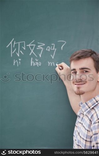 Portrait of smiling male teacher in front of chalkboard writing