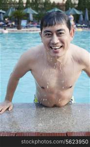 Portrait of smiling man exiting the pool and looking at camera