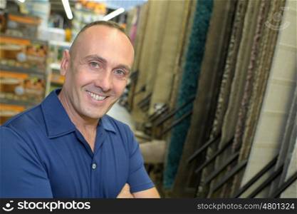 portrait of smiling man standing with carpets in household