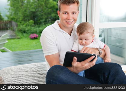 Portrait of smiling man using digital tablet while sitting with child