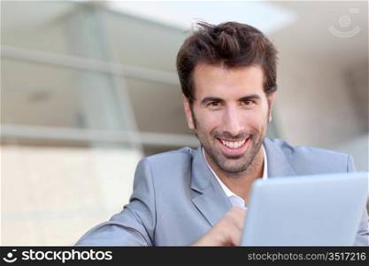 Portrait of smiling man using electronic tablet outside