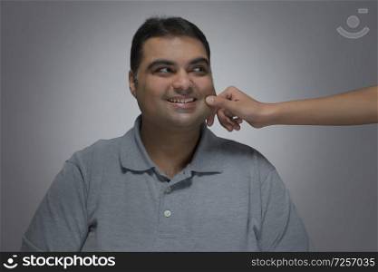 Portrait of smiling man with a hand pulling his cheek