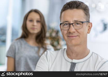 Portrait of smiling man with daughter standing in background at home