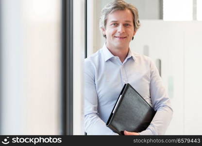 Portrait of smiling mature businesswoman holding file in office