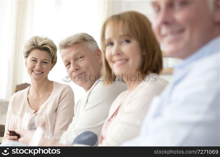 Portrait of smiling mature friends sitting at home