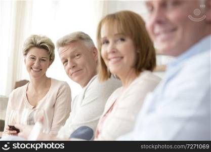 Portrait of smiling mature friends sitting at home