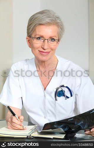 Portrait of smiling mature nurse in office looking at xray