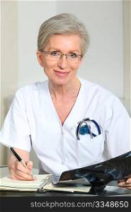 Portrait of smiling mature nurse in office looking at xray