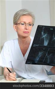 Portrait of smiling mature nurse in office looking at xray