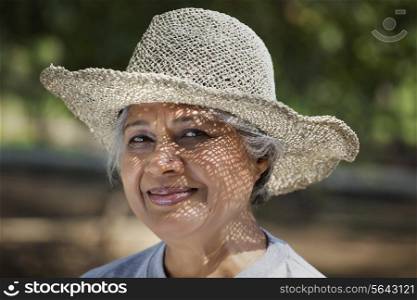 Portrait of smiling mature woman wearing hat at park