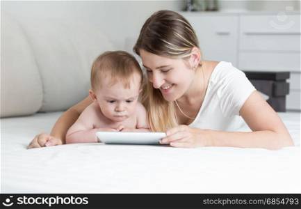 Portrait of smiling mother and baby boy using tablet PC as lying on bed