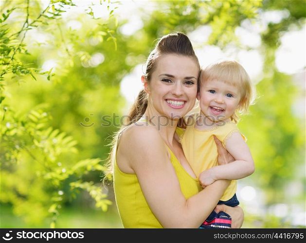 Portrait of smiling mother and baby girl outdoors