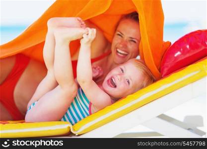Portrait of smiling mother and baby laying on chaise-longue