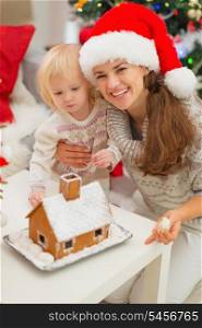 Portrait of smiling mother and baby near Christmas Gingerbread house
