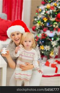 Portrait of smiling mother and baby with Christmas tree cookies