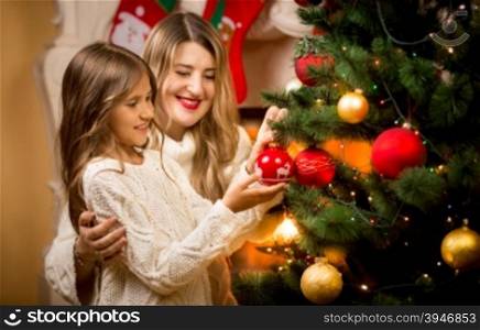 Portrait of smiling mother decorating Christmas tree with daughter