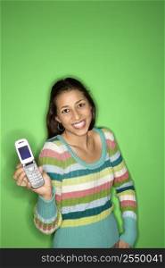 Portrait of smiling Multi-racial teen girl holding cellphone out standing in front of green background.