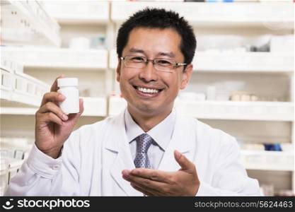 Portrait of smiling pharmacist holding a prescription medication bottle in his hand