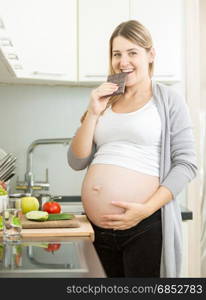 Portrait of smiling pregnant woman posing with chocolate bar