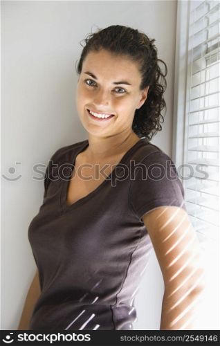 Portrait of smiling pretty young adult Caucasian brunette female standing and looking at viewer.