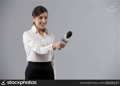 Portrait of smiling reporter holding out microphone
