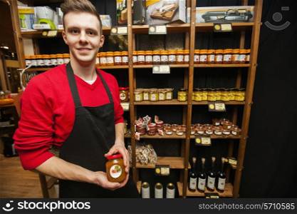 Portrait of smiling salesperson holding jar in supermarket