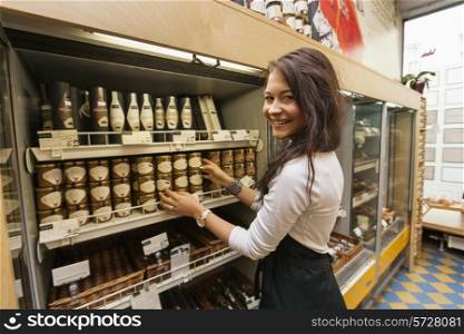 Portrait of smiling saleswoman arranding products in supermarket