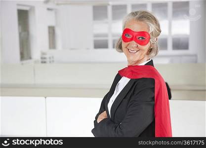 Portrait of smiling senior businesswoman in superhero costume in office