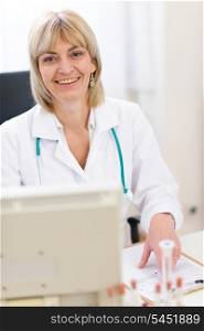 Portrait of smiling senior doctor woman working on computer