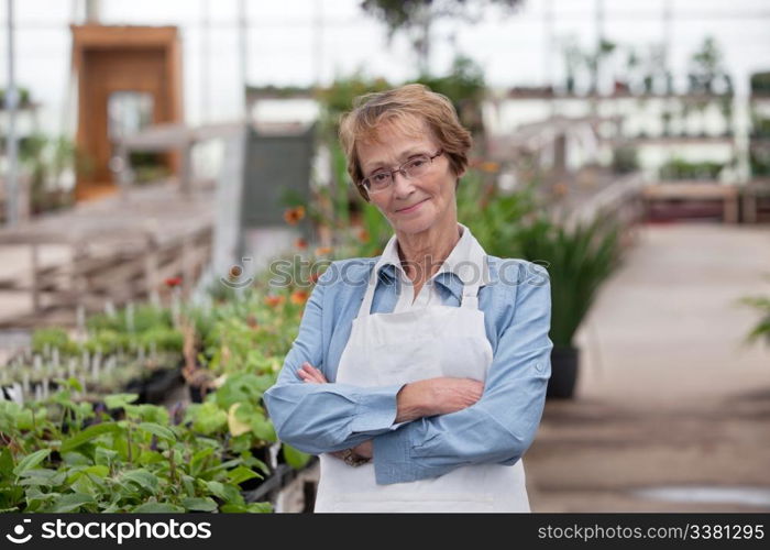 Portrait of smiling senior female worker standing with arms crossed