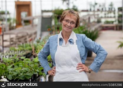 Portrait of smiling senior female worker standing with hands on hip