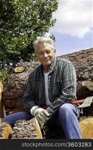 Portrait of smiling senior man sitting on logs