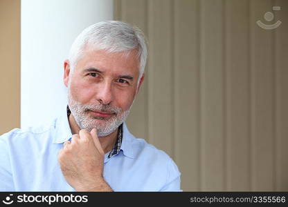 Portrait of smiling senior man with hand on chin