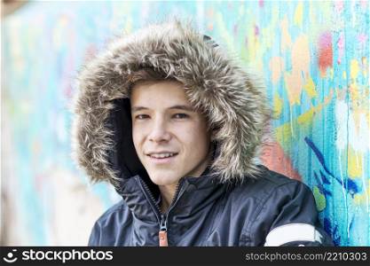Portrait of smiling teen with hooded jacket looking at camera