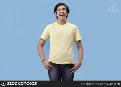 Portrait of smiling teenage boy gesturing while standing against blue background