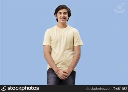 Portrait of smiling teenage boy gesturing while standing against blue background