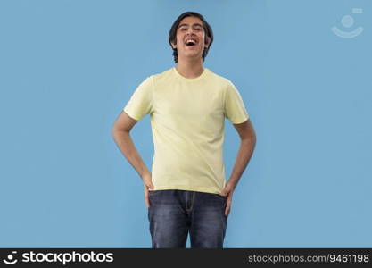 Portrait of smiling teenage boy gesturing while standing against blue background