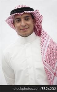 Portrait of smiling teenage boy in traditional Arab clothing, studio shot
