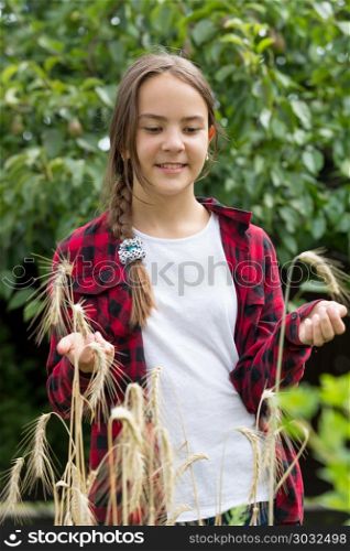 Portrait of smiling teenage girl in red checkered shirt posing with ripe wheat in field. Smiling teenage girl in red checkered shirt posing with ripe wheat in field