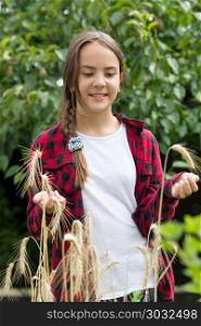 Portrait of smiling teenage girl in red checkered shirt posing with ripe wheat in field. Smiling teenage girl in red checkered shirt posing with ripe wheat in field